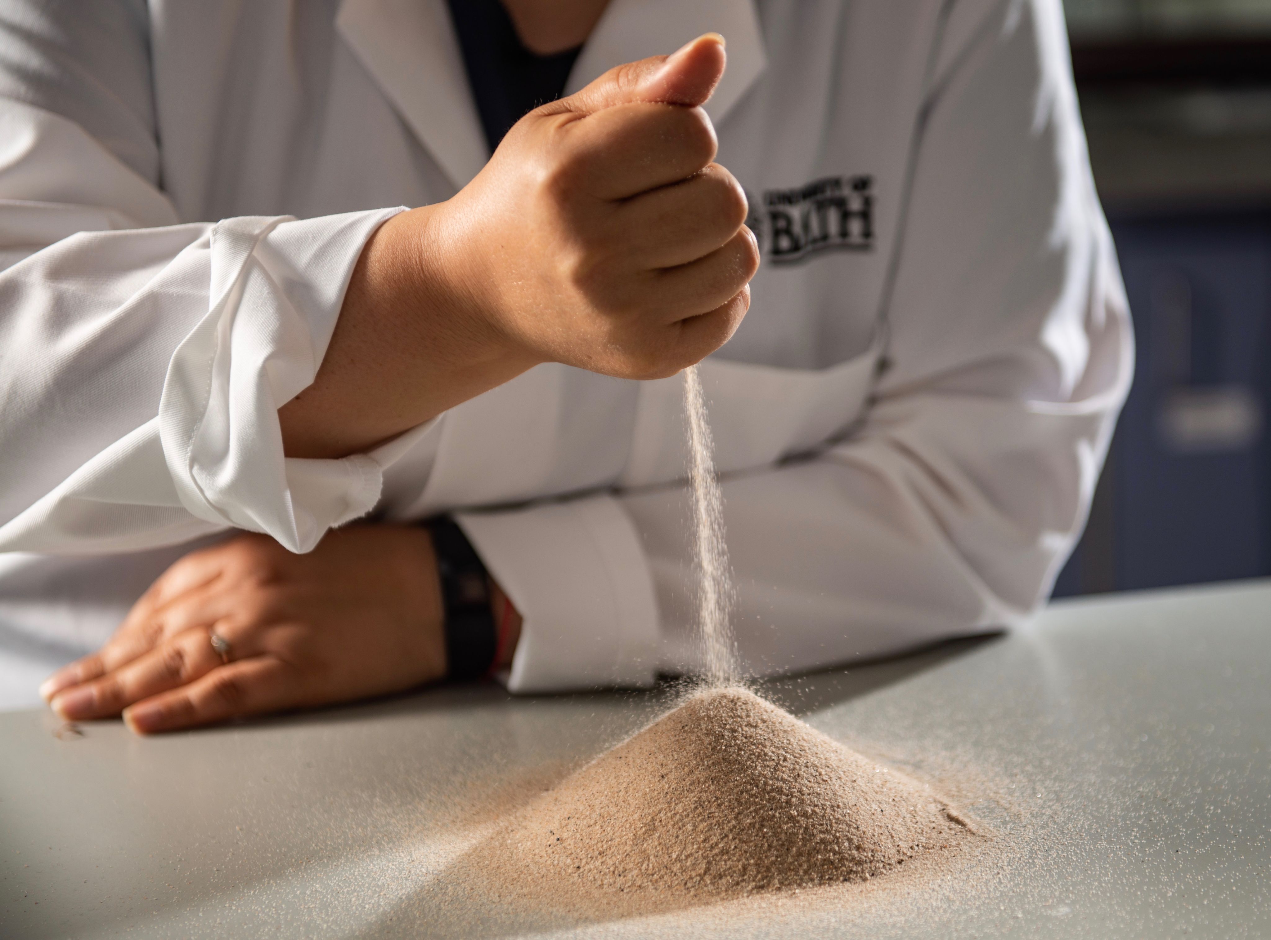 Sand runs through a hand into a small pile